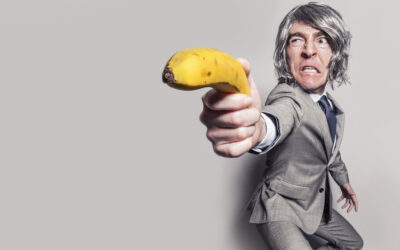 Mann i dress sikter på deg med en banan